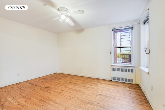 unfurnished room with radiator heating unit, light wood finished floors, ceiling fan, and baseboards