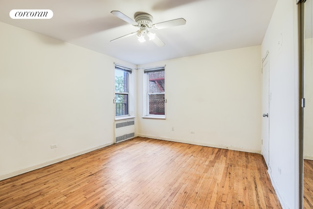 unfurnished room with radiator heating unit, light wood-style floors, ceiling fan, and baseboards