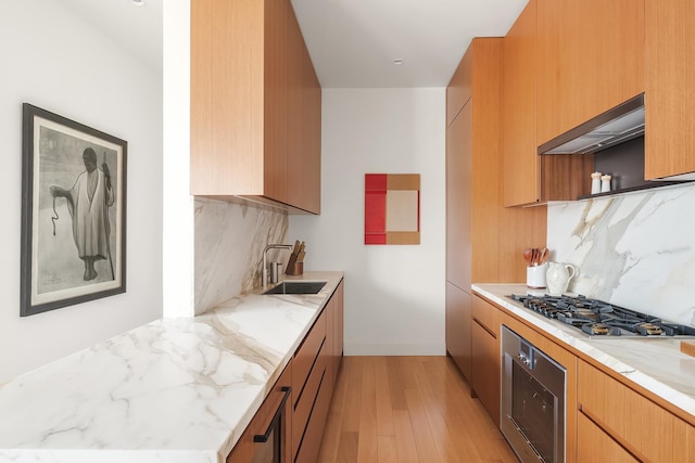 15 E 30th St Unit 21C, New York City, NY 10016 - kitchen with stainless steel gas cooktop, wall oven, tasteful backsplash, under cabinet range hood, and light stone counters