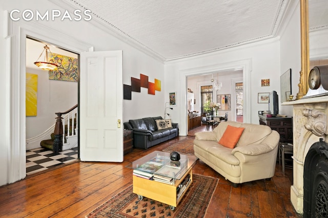 living area with wood-type flooring, stairs, and crown molding