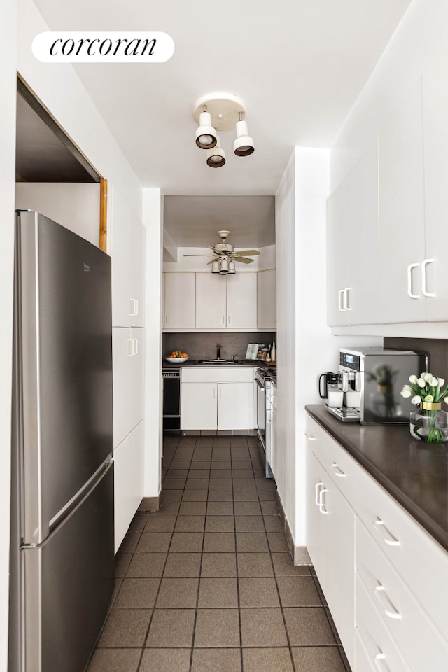 kitchen featuring stainless steel appliances, dark countertops, white cabinetry, dark tile patterned floors, and tasteful backsplash