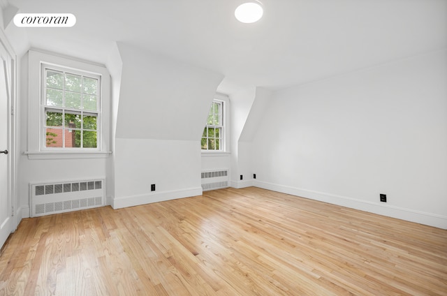 bonus room with radiator heating unit, vaulted ceiling, light wood finished floors, and baseboards
