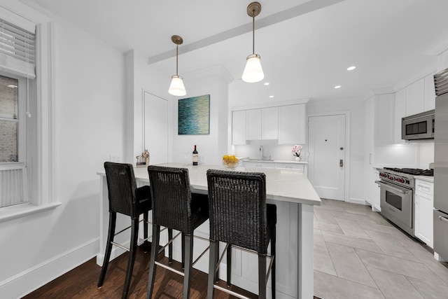 kitchen with appliances with stainless steel finishes, white cabinetry, a kitchen bar, decorative light fixtures, and recessed lighting