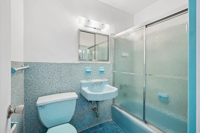 1655 Flatbush Ave Unit C2105, New York City, NY 11210 - bathroom with toilet, tile patterned flooring, bath / shower combo with glass door, a wainscoted wall, and a sink