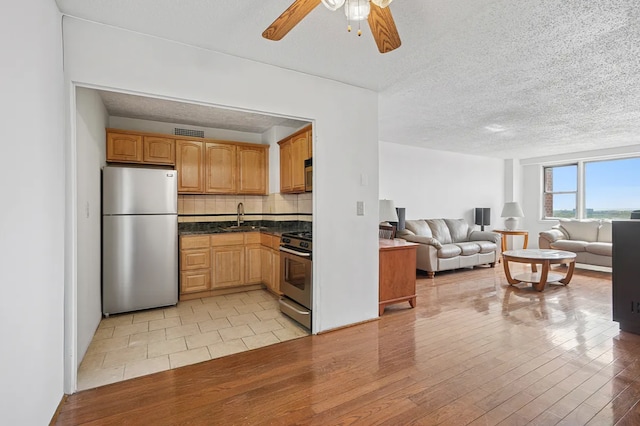 1655 Flatbush Ave Unit C2105, New York City, NY 11210 - kitchen featuring appliances with stainless steel finishes, a sink, open floor plan, dark countertops, and light wood-style flooring