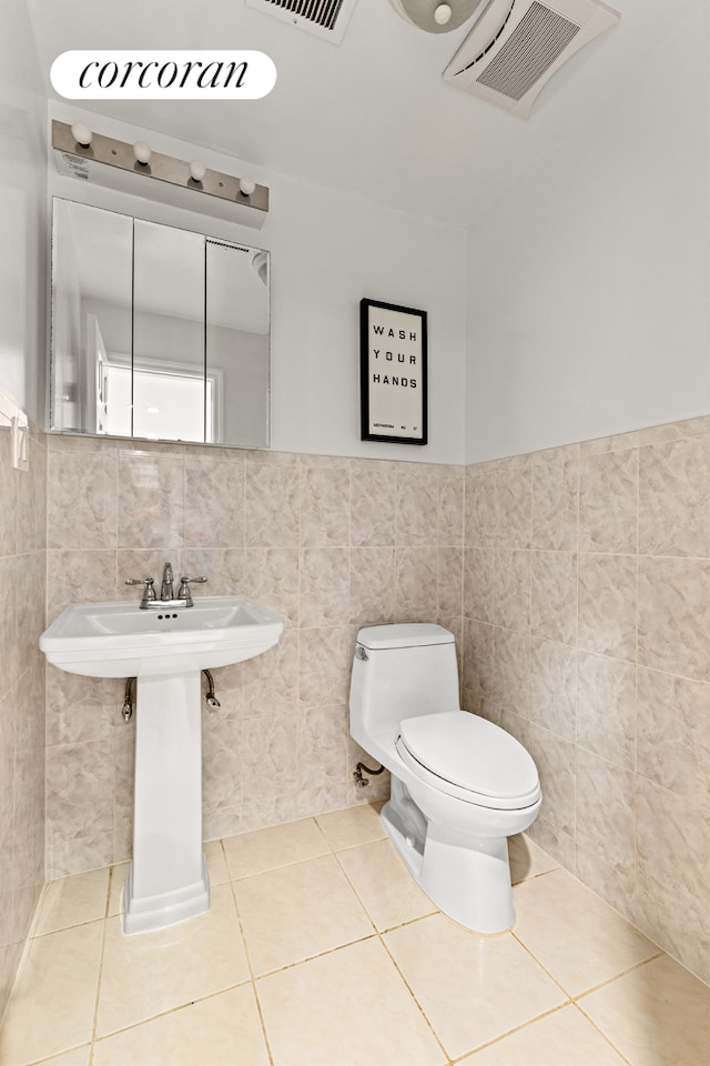 195 Bch 125th St Unit 1C, New York City, NY 11694 - bathroom with tile walls, toilet, tile patterned floors, wainscoting, and a sink