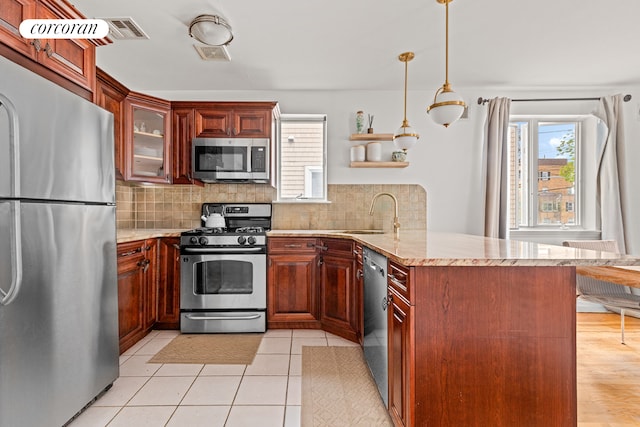 195 Bch 125th St Unit 1C, New York City, NY 11694 - kitchen featuring appliances with stainless steel finishes, a peninsula, a sink, decorative backsplash, and glass insert cabinets