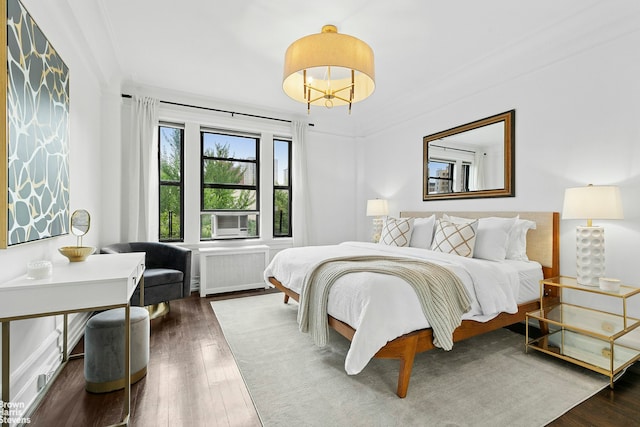 bedroom with radiator heating unit, cooling unit, wood finished floors, and ornamental molding