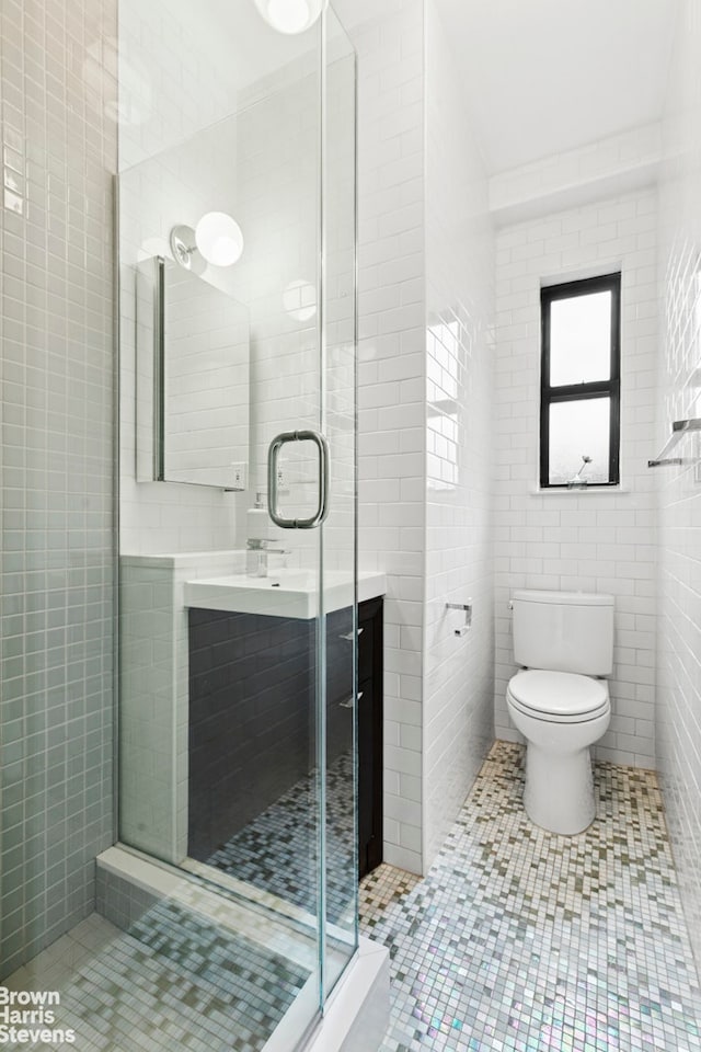 bathroom featuring tile walls, a stall shower, vanity, tile patterned flooring, and toilet