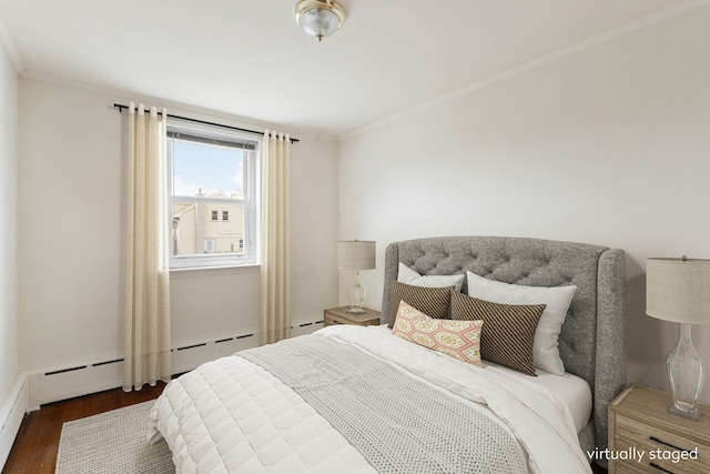 bedroom featuring ornamental molding, wood finished floors, and a baseboard heating unit