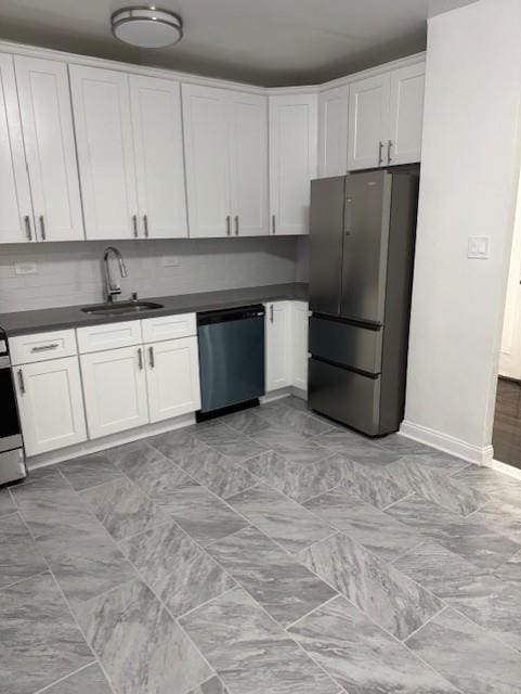 kitchen featuring freestanding refrigerator, dishwasher, a sink, dark countertops, and white cabinetry