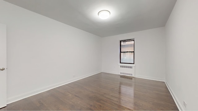 221 E 18th St Unit 1E, New York City, NY 11226 - spare room featuring baseboards and dark wood-type flooring