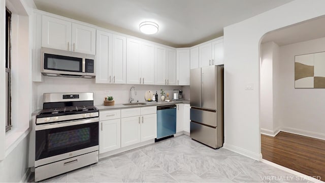 221 E 18th St Unit 1E, New York City, NY 11226 - kitchen featuring stainless steel appliances, a sink, white cabinets, and baseboards