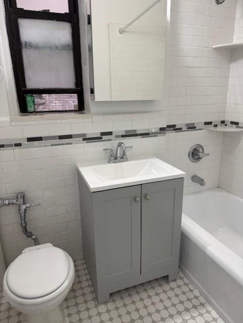 bathroom featuring bathing tub / shower combination, tile walls, vanity, tile patterned flooring, and toilet
