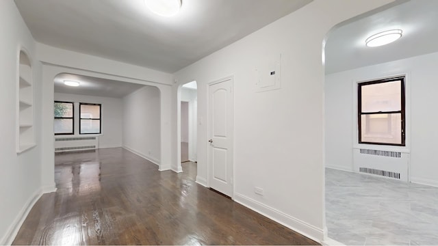 221 E 18th St Unit 1E, New York City, NY 11226 - hallway with radiator heating unit, arched walkways, electric panel, and wood finished floors