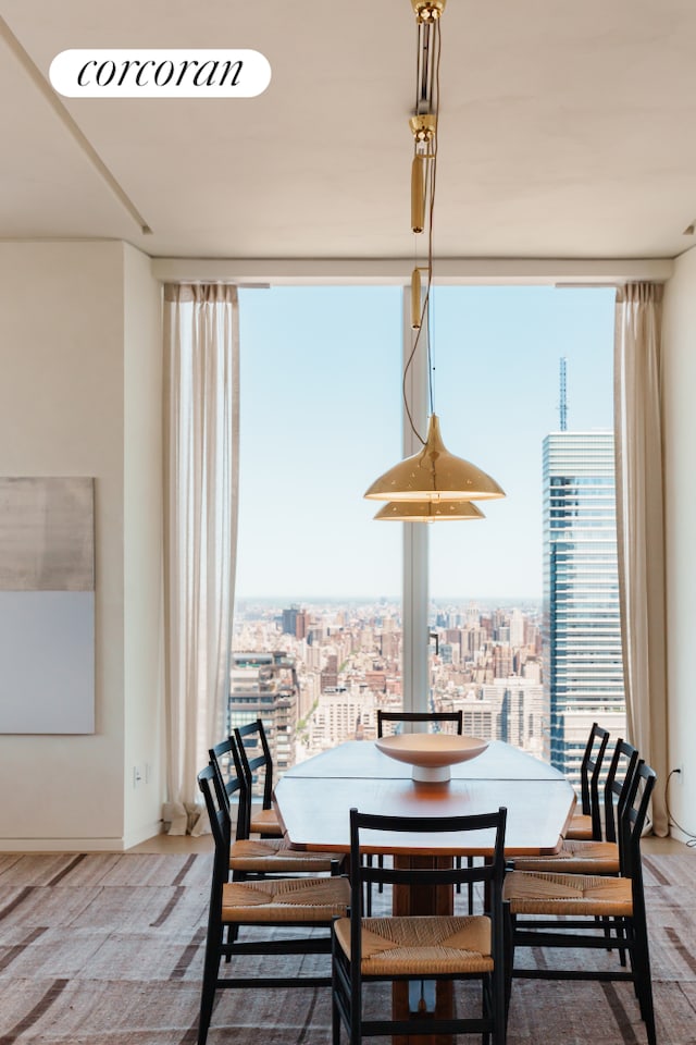 dining space featuring expansive windows, healthy amount of natural light, a view of city, and baseboards