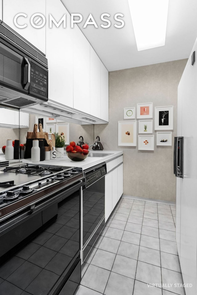 kitchen featuring black appliances, white cabinetry, light countertops, a sink, and light tile patterned flooring