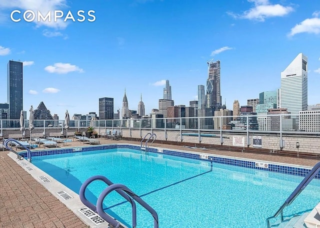 community pool featuring a skyline view and fence