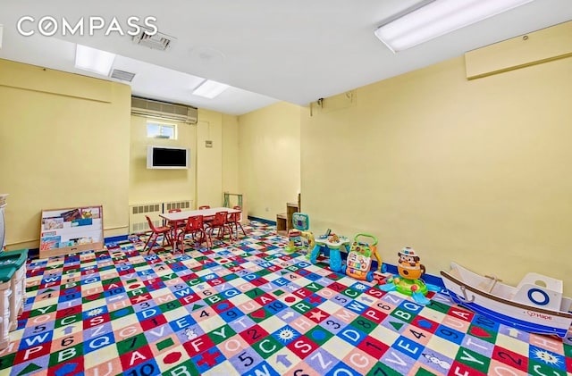 game room with a wall mounted AC and radiator