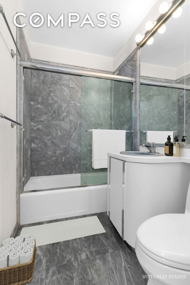 400 E 56th St Unit 38S, New York City, NY 10022 - bathroom with vanity, bath / shower combo with glass door, toilet, and marble look tiles