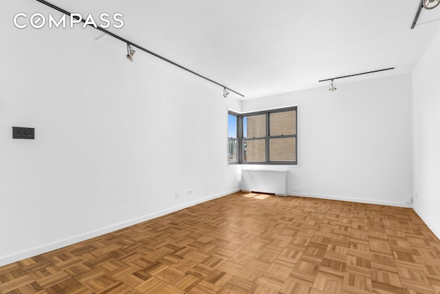 unfurnished room featuring rail lighting and baseboards