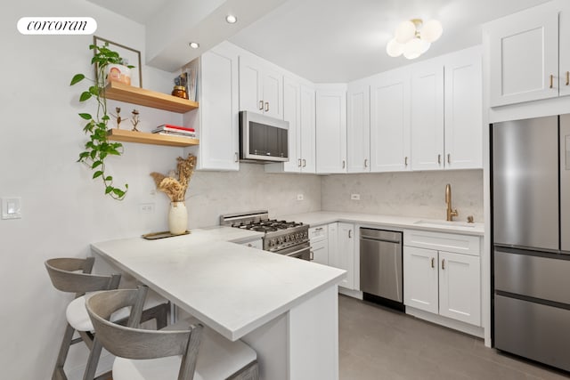 kitchen featuring stainless steel appliances, a sink, backsplash, light countertops, and white cabinetry