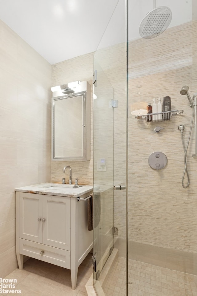 bathroom with a stall shower, tile walls, and vanity