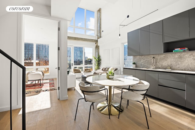 dining space featuring light wood-type flooring, a towering ceiling, and a city view