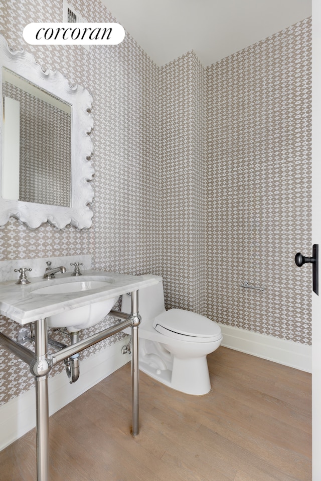 bathroom with wood finished floors, toilet, and baseboards