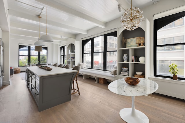 dining area with beam ceiling, wood finished floors, and a chandelier