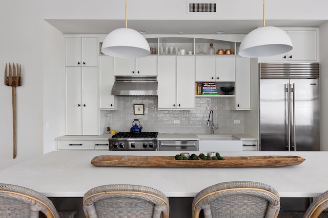 kitchen with under cabinet range hood, stainless steel built in fridge, a sink, range, and backsplash