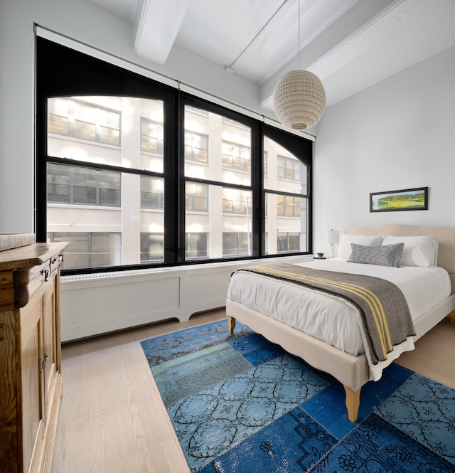 bedroom with wood finished floors and beam ceiling