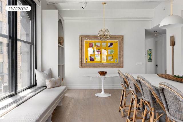 dining space featuring healthy amount of natural light, wood finished floors, baseboards, and beamed ceiling