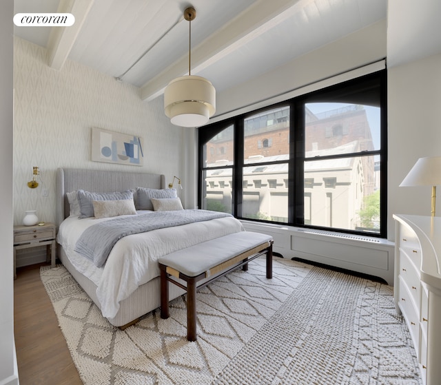 bedroom with beam ceiling, wallpapered walls, multiple windows, and light wood finished floors