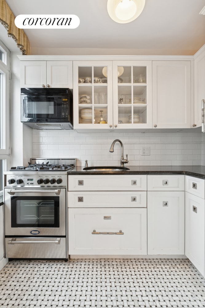 kitchen with black microwave, high end stainless steel range, a sink, and dark countertops