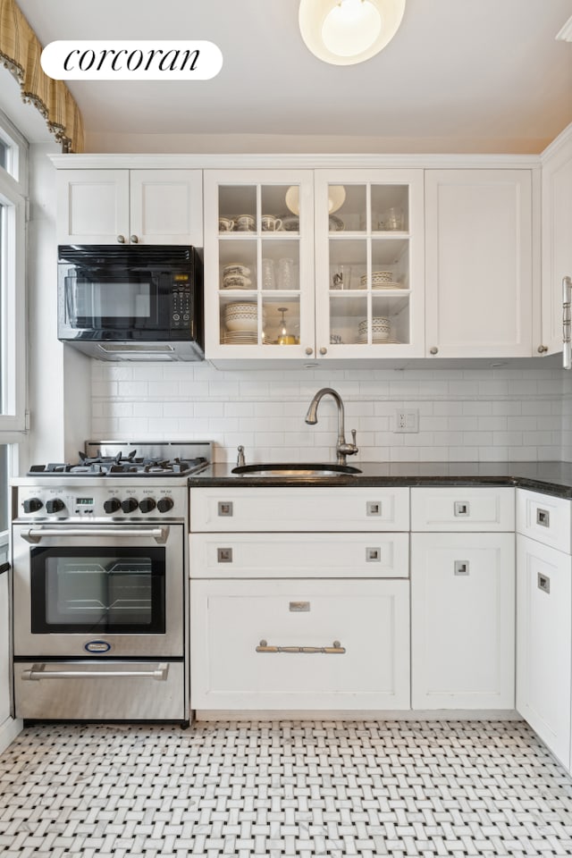kitchen with black microwave, high end stainless steel range, a sink, and dark countertops