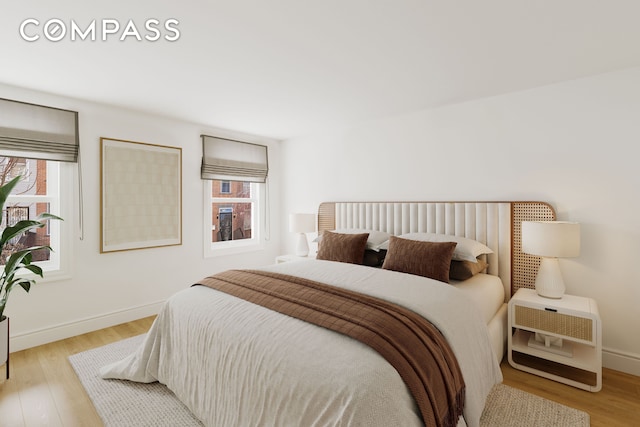 bedroom featuring light wood-style floors, multiple windows, and baseboards