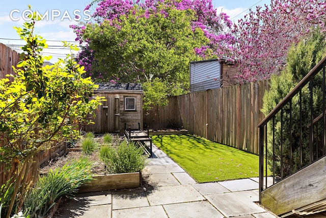 view of yard with a shed, an outdoor structure, a garden, and a patio