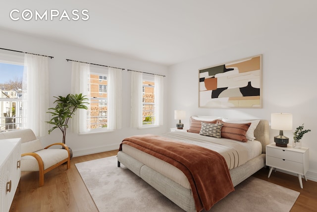 bedroom featuring multiple windows, wood finished floors, and baseboards