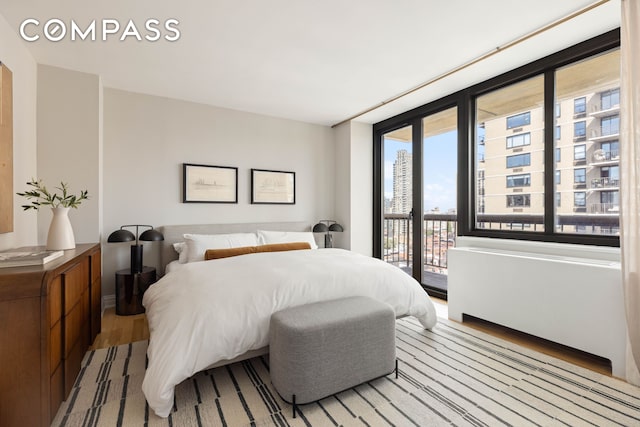 bedroom featuring access to outside, wood finished floors, and baseboards
