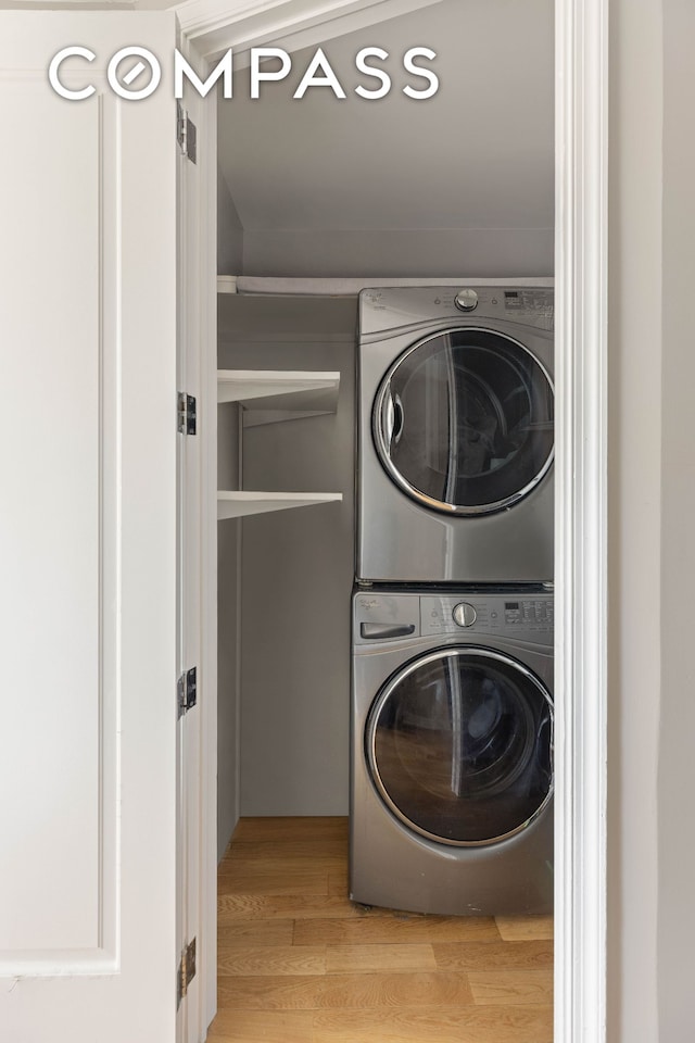 washroom with stacked washer / drying machine and light wood-style floors