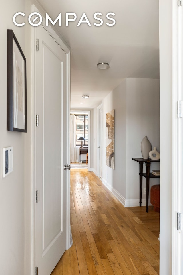 hallway featuring baseboards and light wood-style floors