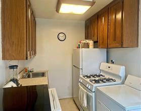 166-30 17th Rd Unit 2, New York City, NY 11357 - kitchen featuring white gas stove, a sink, light countertops, and brown cabinetry