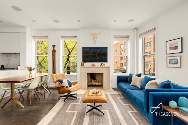 living room featuring crown molding, wood finished floors, healthy amount of natural light, and a fireplace with flush hearth