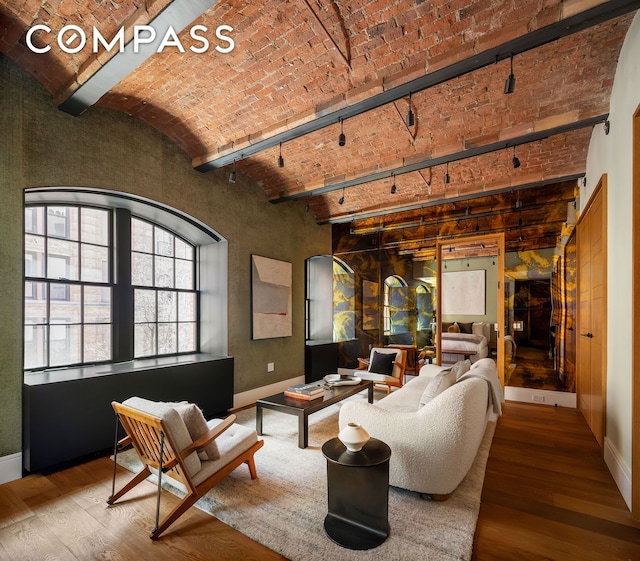 living area with hardwood / wood-style flooring, brick ceiling, baseboards, and arched walkways