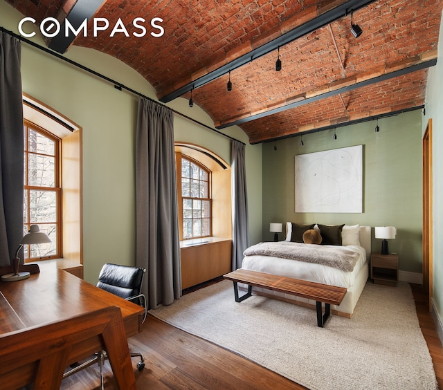 bedroom with brick ceiling, wood finished floors, baseboards, and an office area