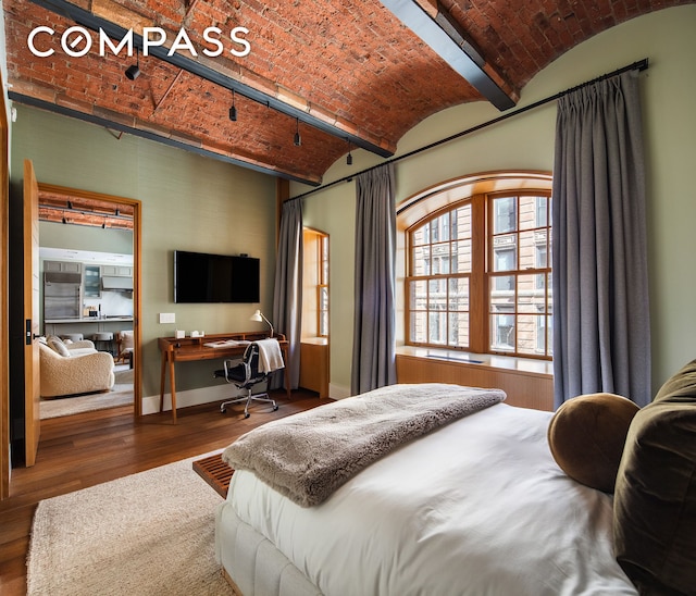 bedroom with brick ceiling, wood finished floors, baseboards, and an office area