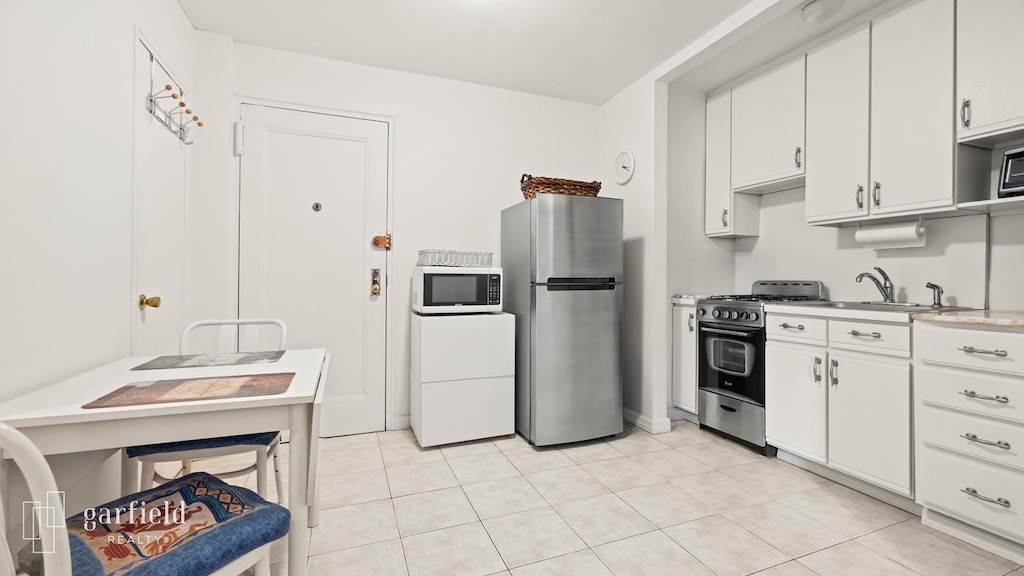 61 Oliver St Unit 2-P, New York City, NY 11209 - kitchen with appliances with stainless steel finishes, light countertops, white cabinetry, and light tile patterned floors