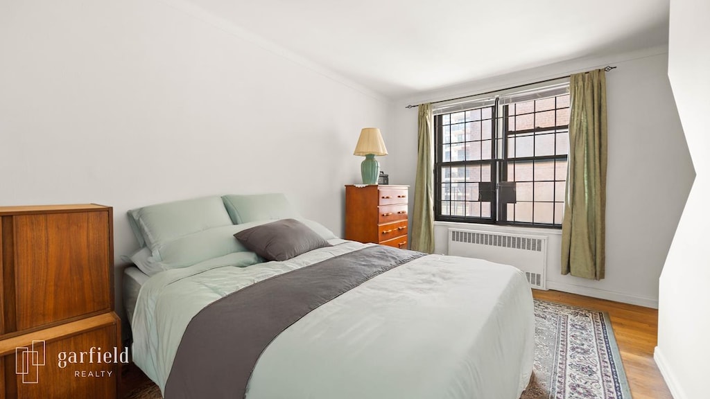 61 Oliver St Unit 2-P, New York City, NY 11209 - bedroom featuring radiator, wood finished floors, and lofted ceiling