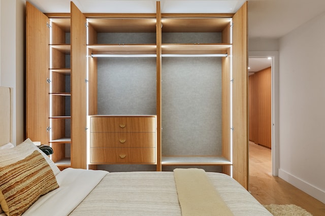 bedroom with wood finished floors, a closet, and baseboards